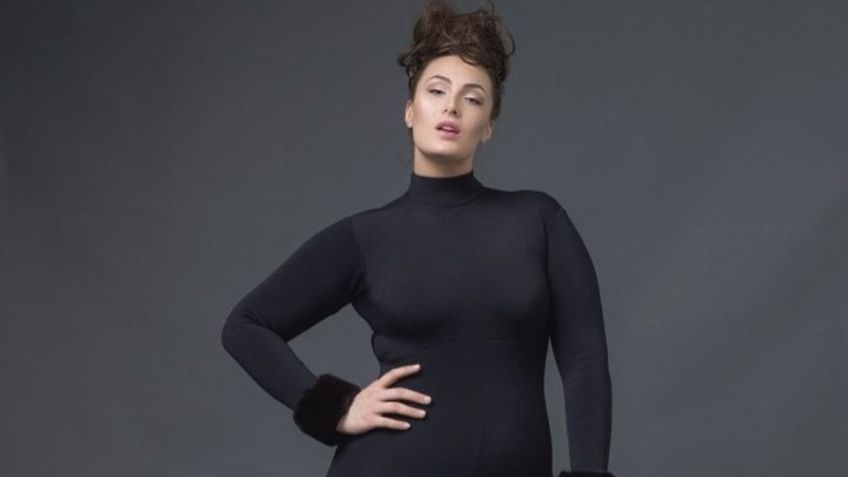 Arissa LeBrock posing in a black dress.